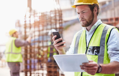 Worker checking mobile phone alert on site
