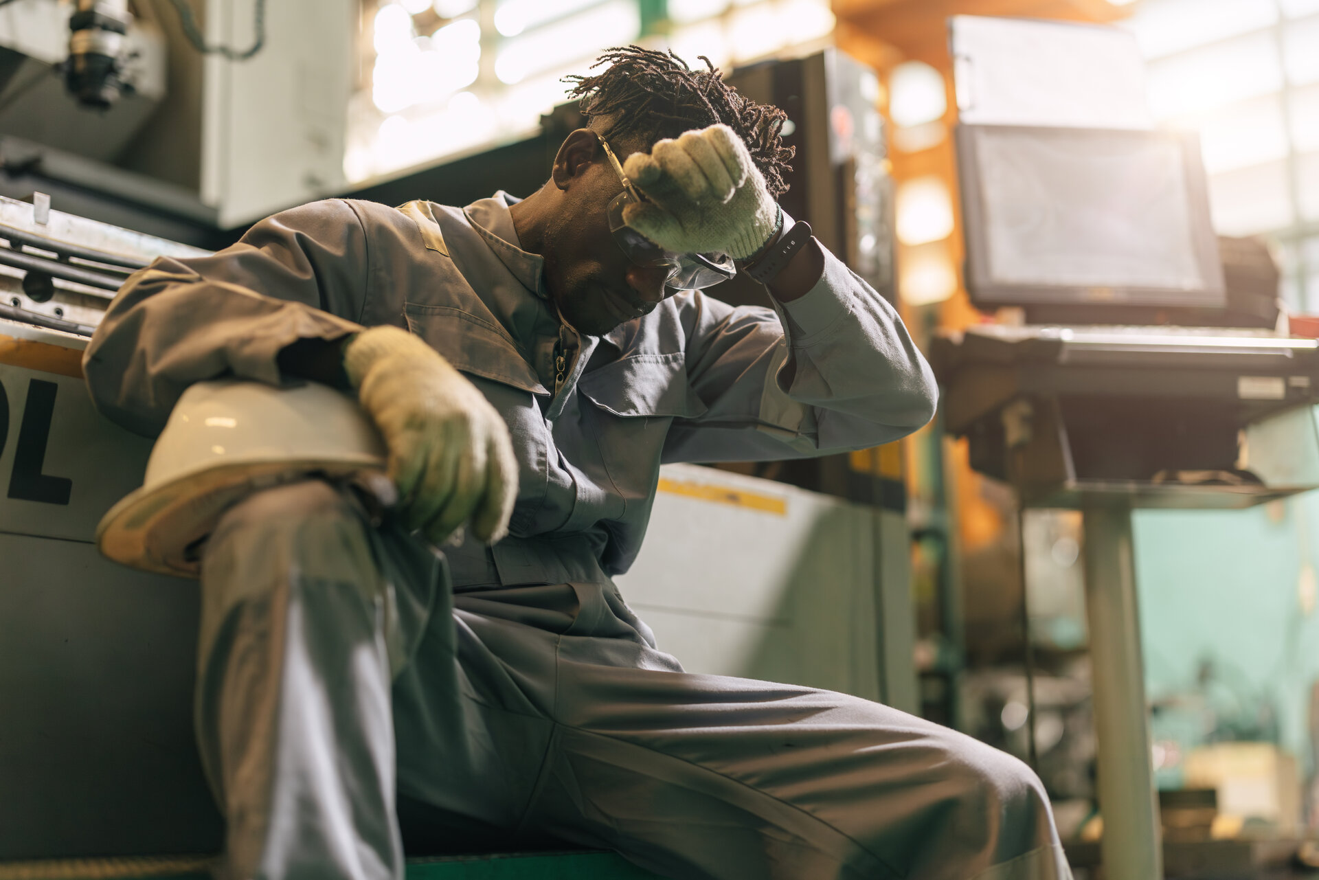 Exhausted industrial worker resting his head, illustrating workplace fatigue