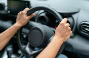Driver hands on steering wheel, illustrating vehicle technology distraction