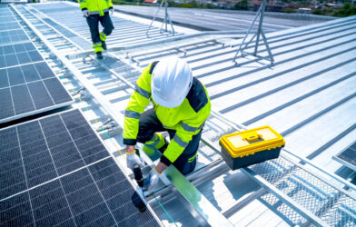 Tradesperson working at height on a rooftop wearing a safety harness