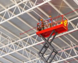 Scissor lift platform elevated toward factory roof