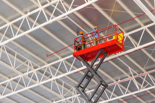 Scissor lift platform elevated toward factory roof