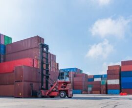 Reach stacker lifting containers at warehouse logistics terminal
