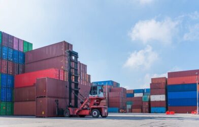 Reach stacker lifting containers at warehouse logistics terminal