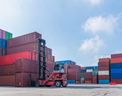 Reach stacker lifting containers at warehouse logistics terminal